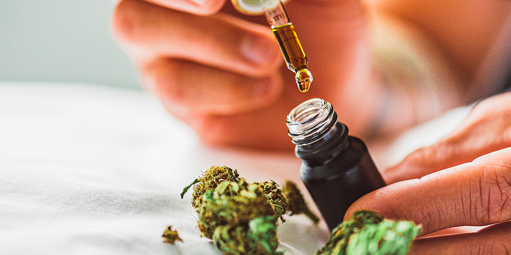 Dropper bottle of CBD oil beside a cannabis leaf, representing the therapeutic use of marijuana.
