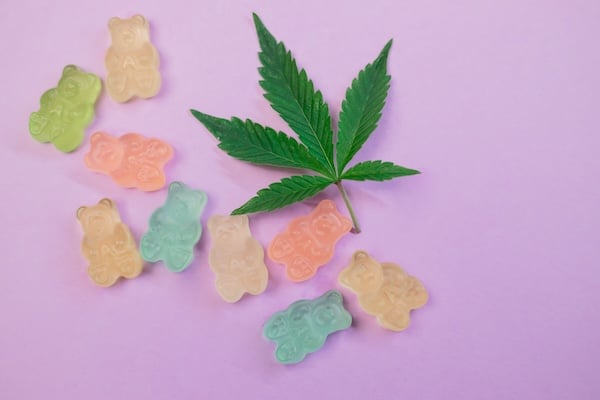 thcv-gummies THCV gummies on a lavender surface with a.green cannabis fan leaf